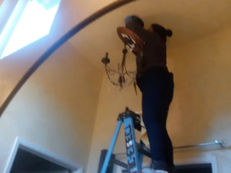 Electrician installing a chandelier in a Glassmanor residence